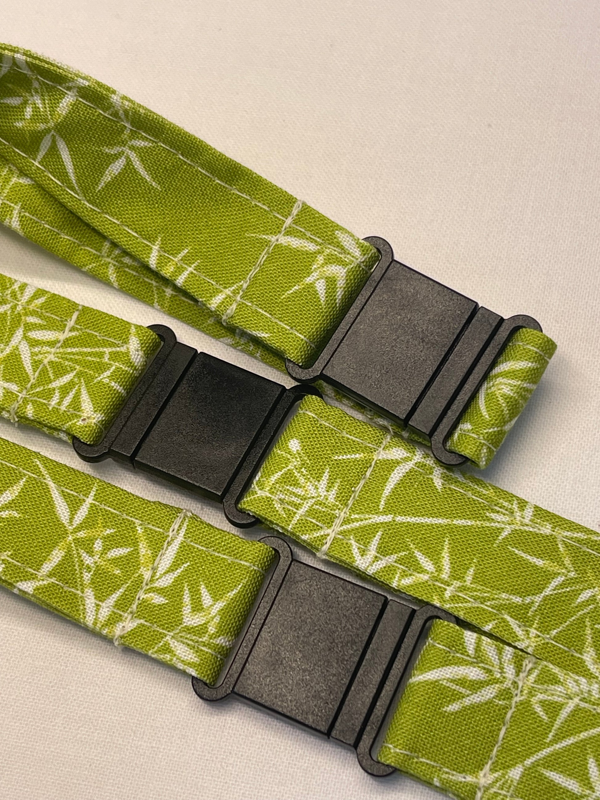 Green fabric strap with black buckles on a beige background