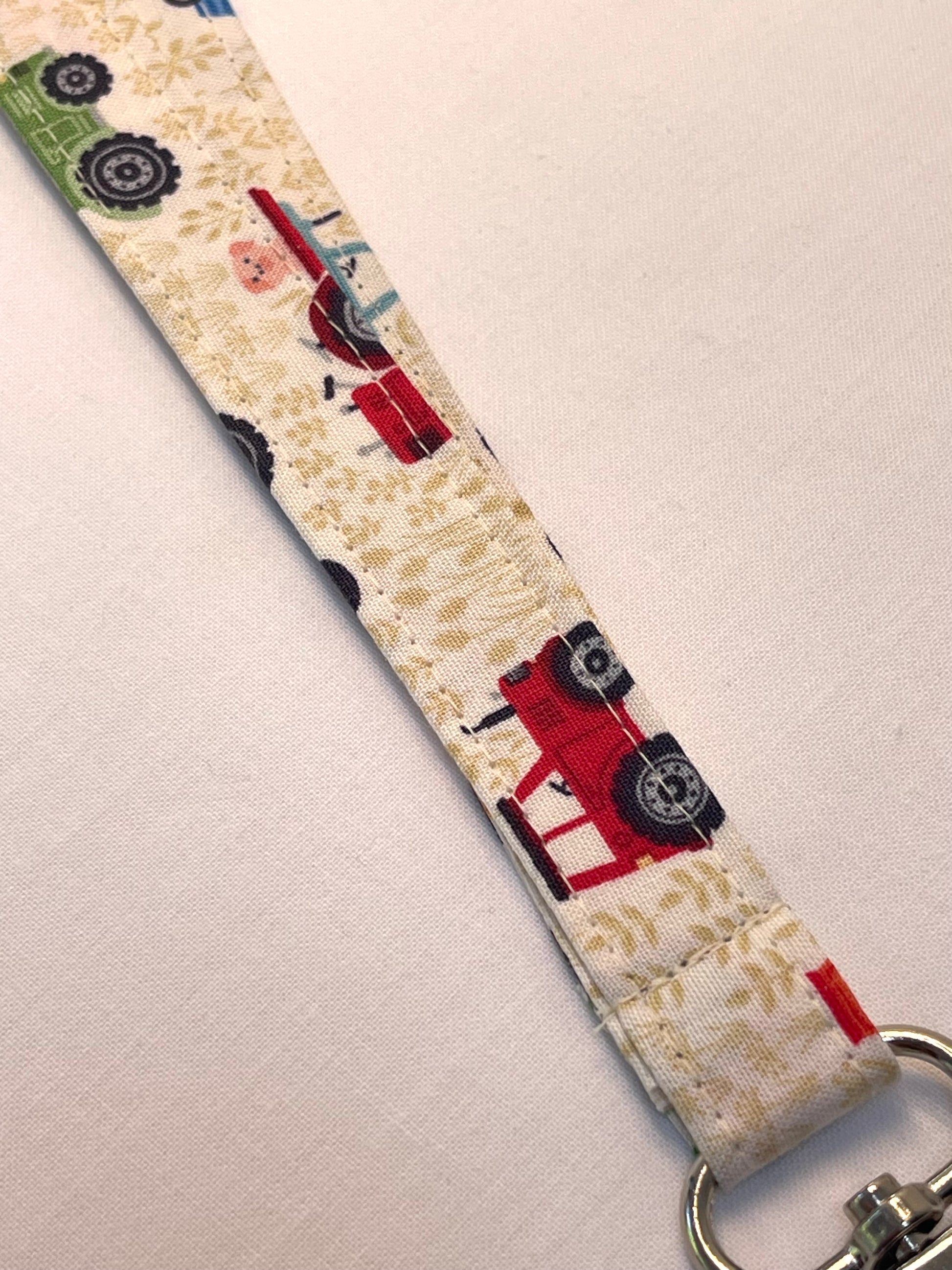 Fabric keychain with red tractors on a beige background