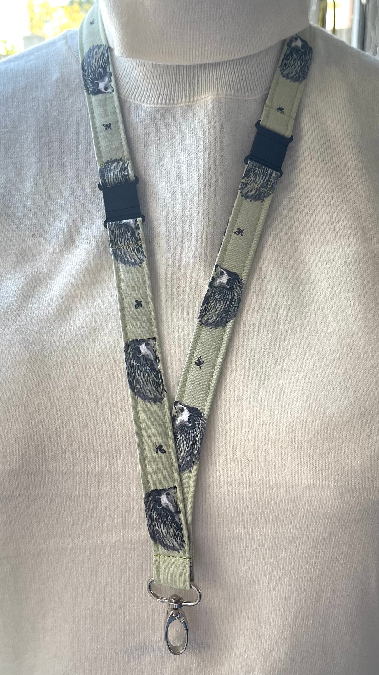 A fabric lanyard featuring a hedgehog pattern, with a safety breakaway clip and a metal keychain attached.