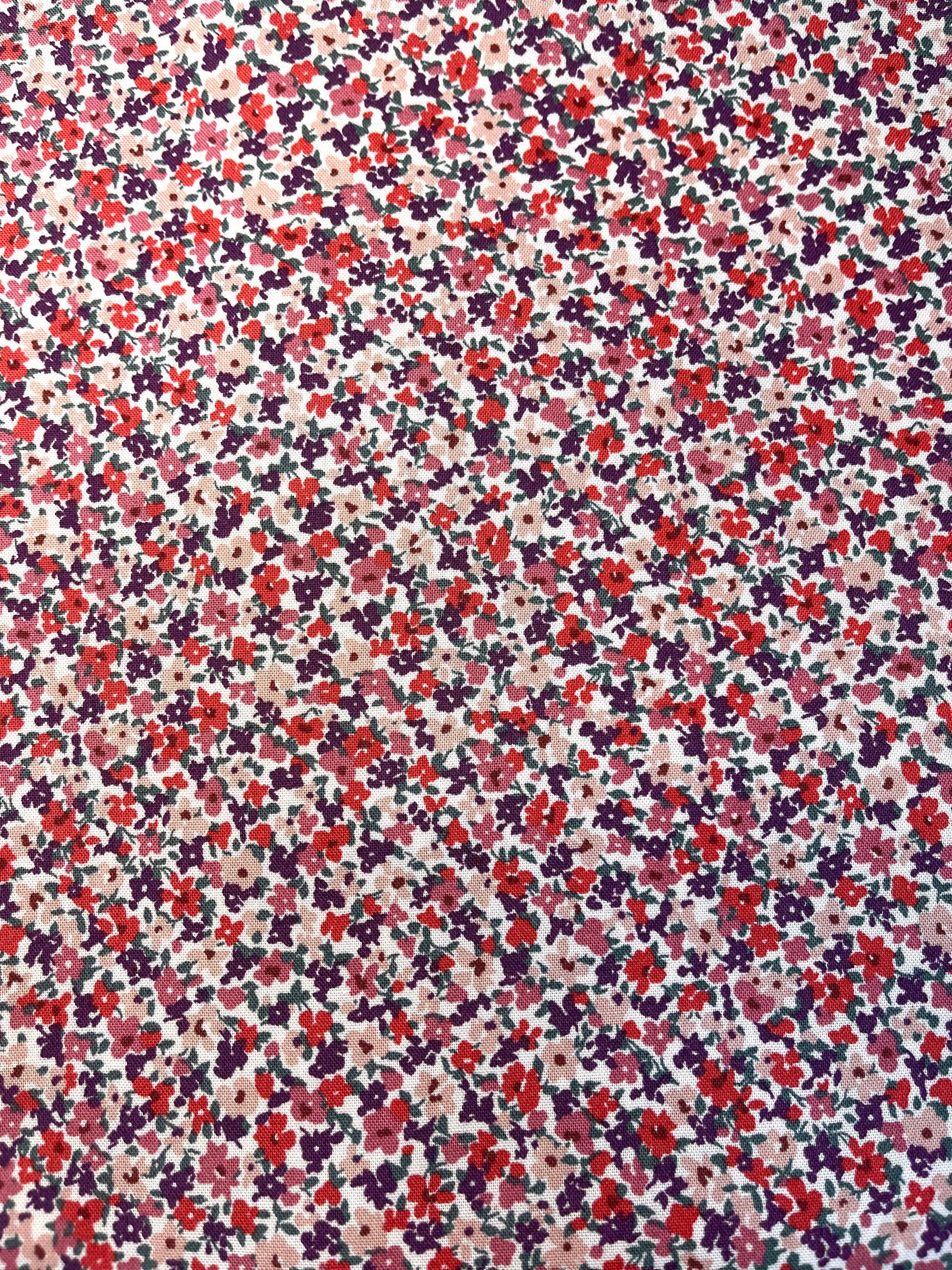 Floral pattern with small flowers in red, purple, and pink on a beige background