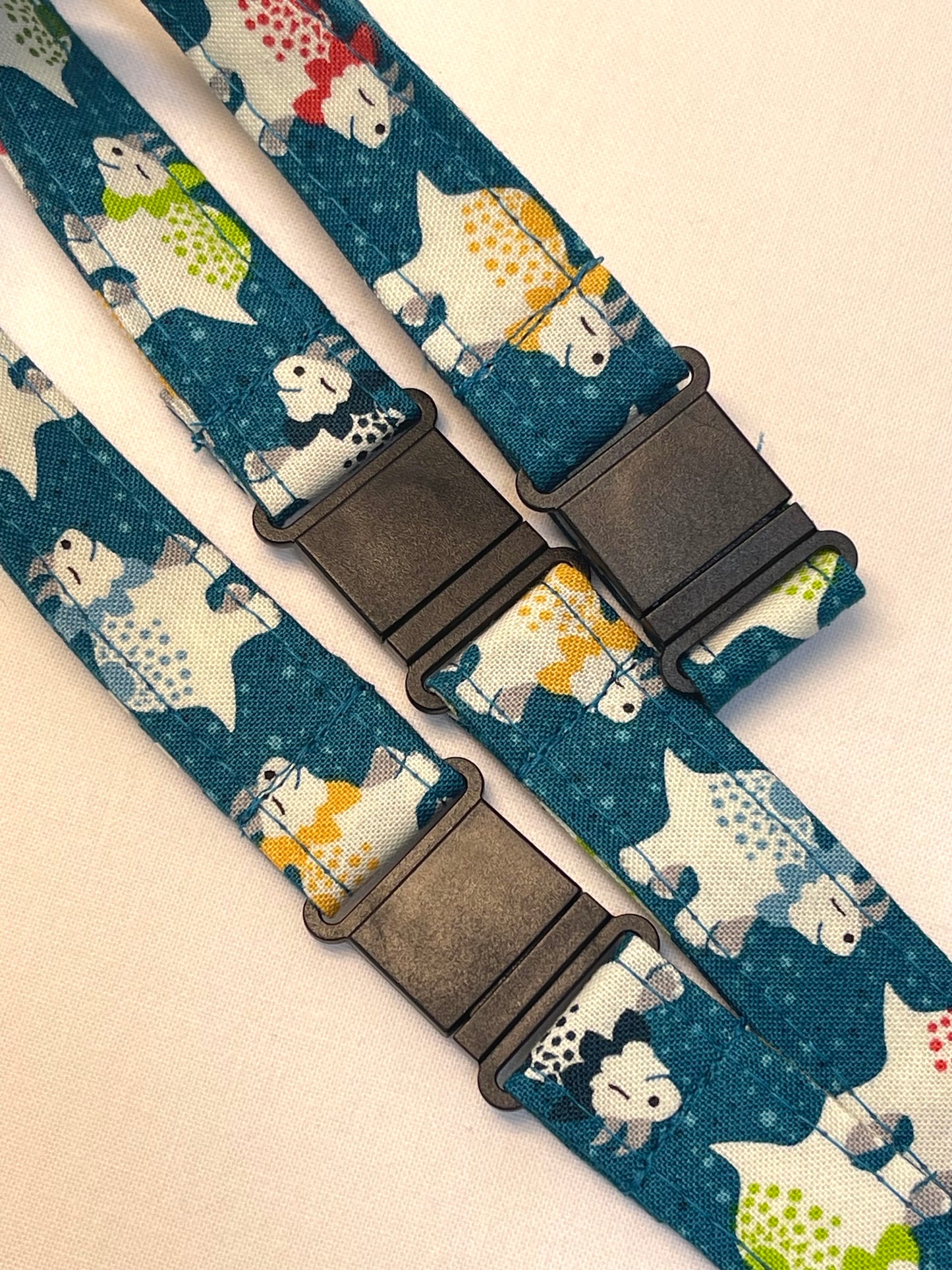 Patterned lanyard with animal design and black plastic breakaway clips on a beige background