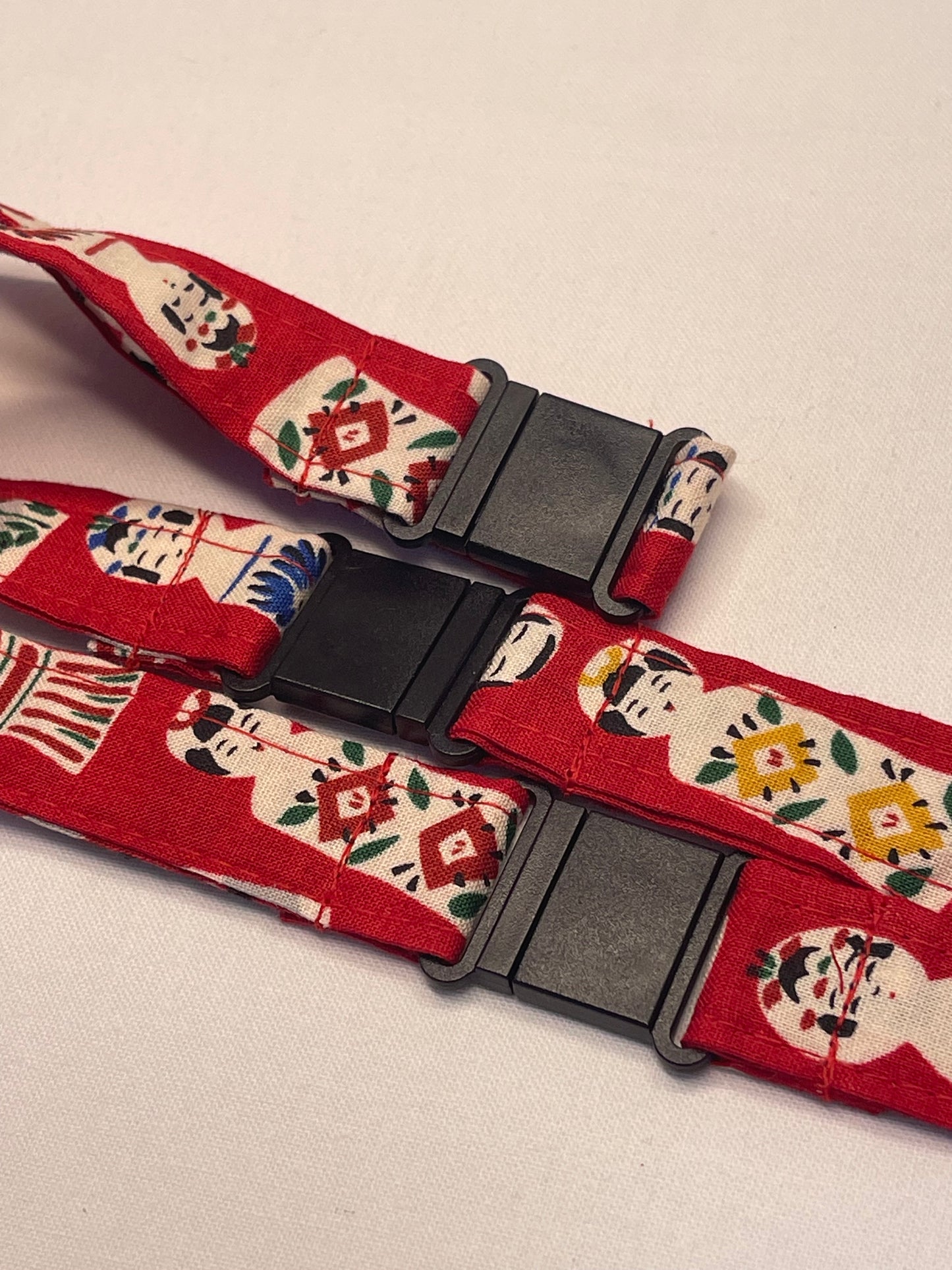 Red lanyard with black buckle and festive design on a light background