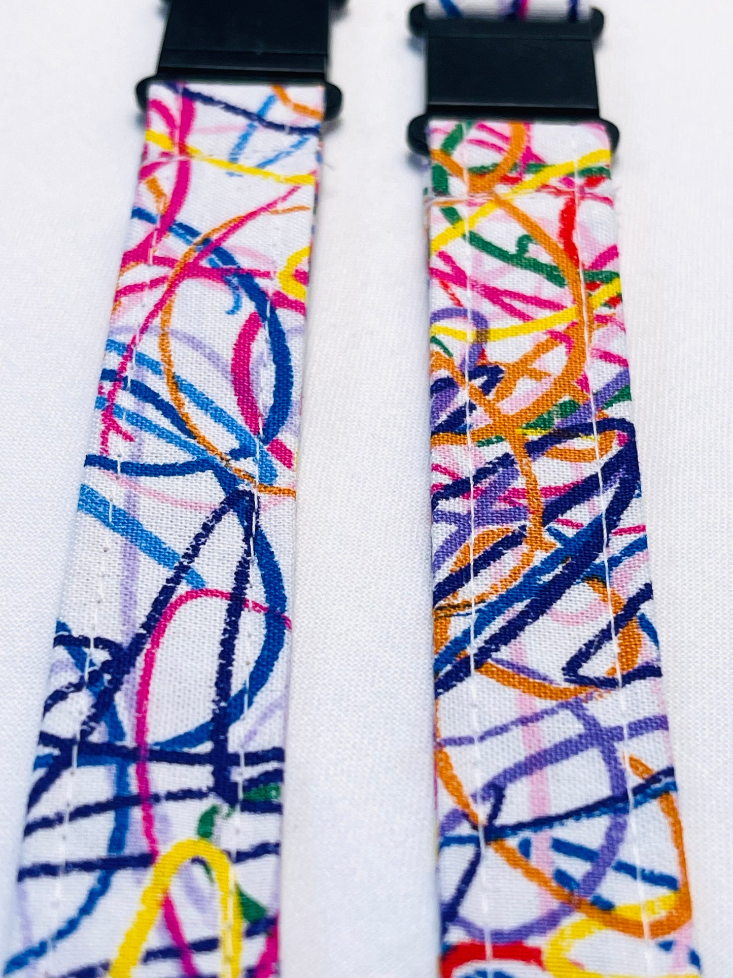 Colorful abstract patterned strap with black buckle on a white background