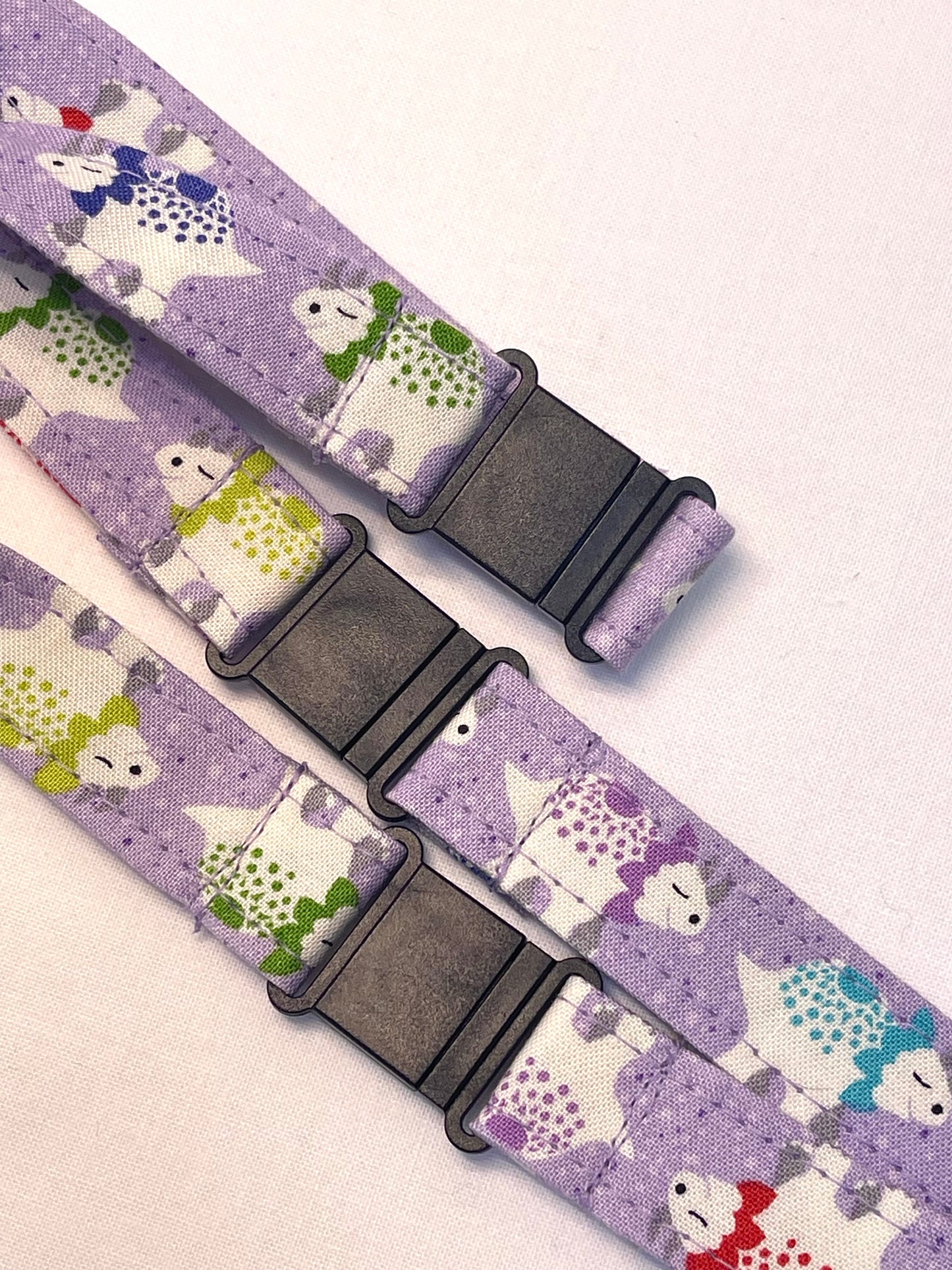 Two fabric straps with a dinosaur pattern on a light purple background