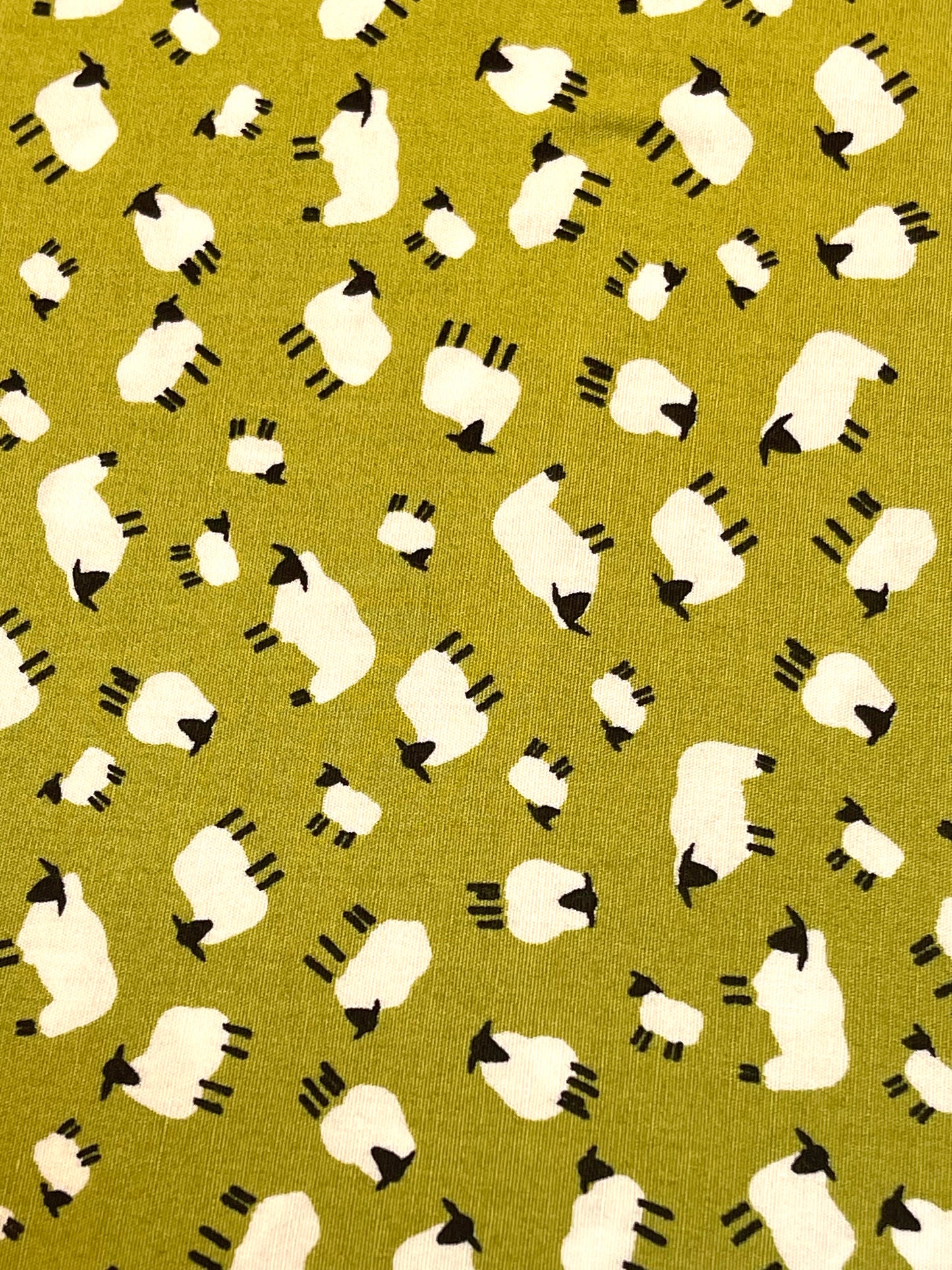 Pattern of white sheep with black faces on a green background
