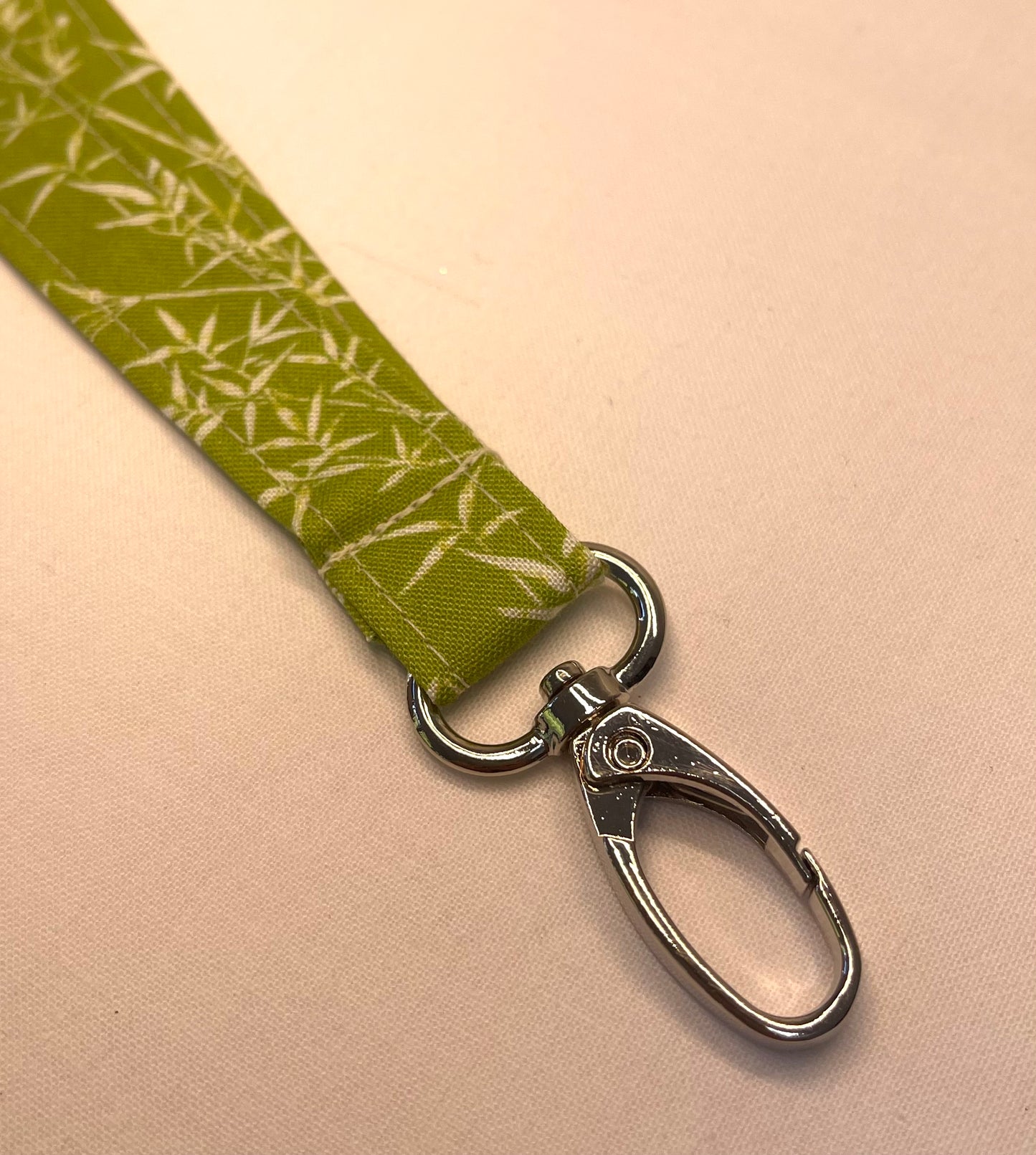 Green lanyard with silver clip on a beige background