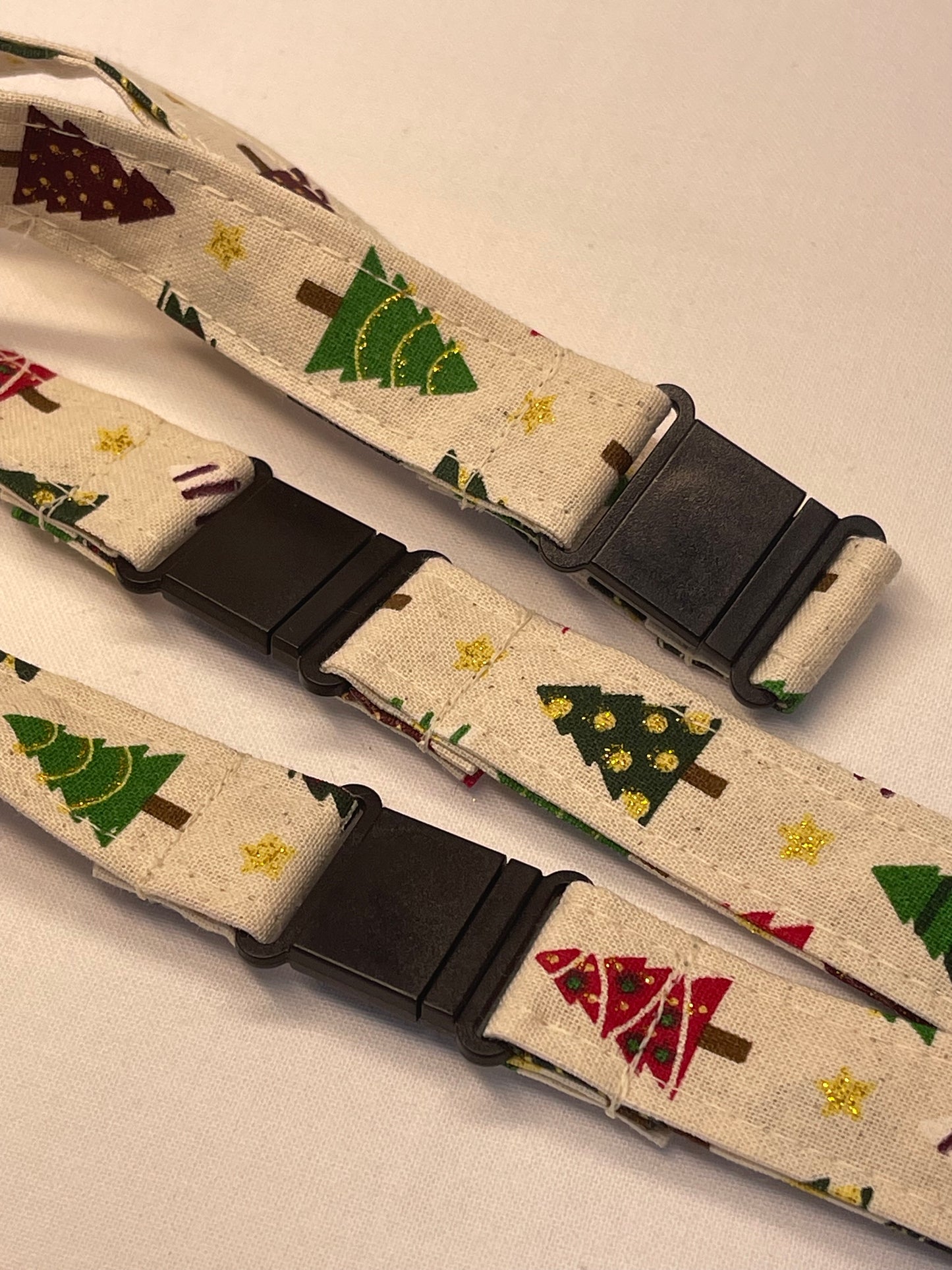 Two fabric straps with Christmas tree patterns on a beige background