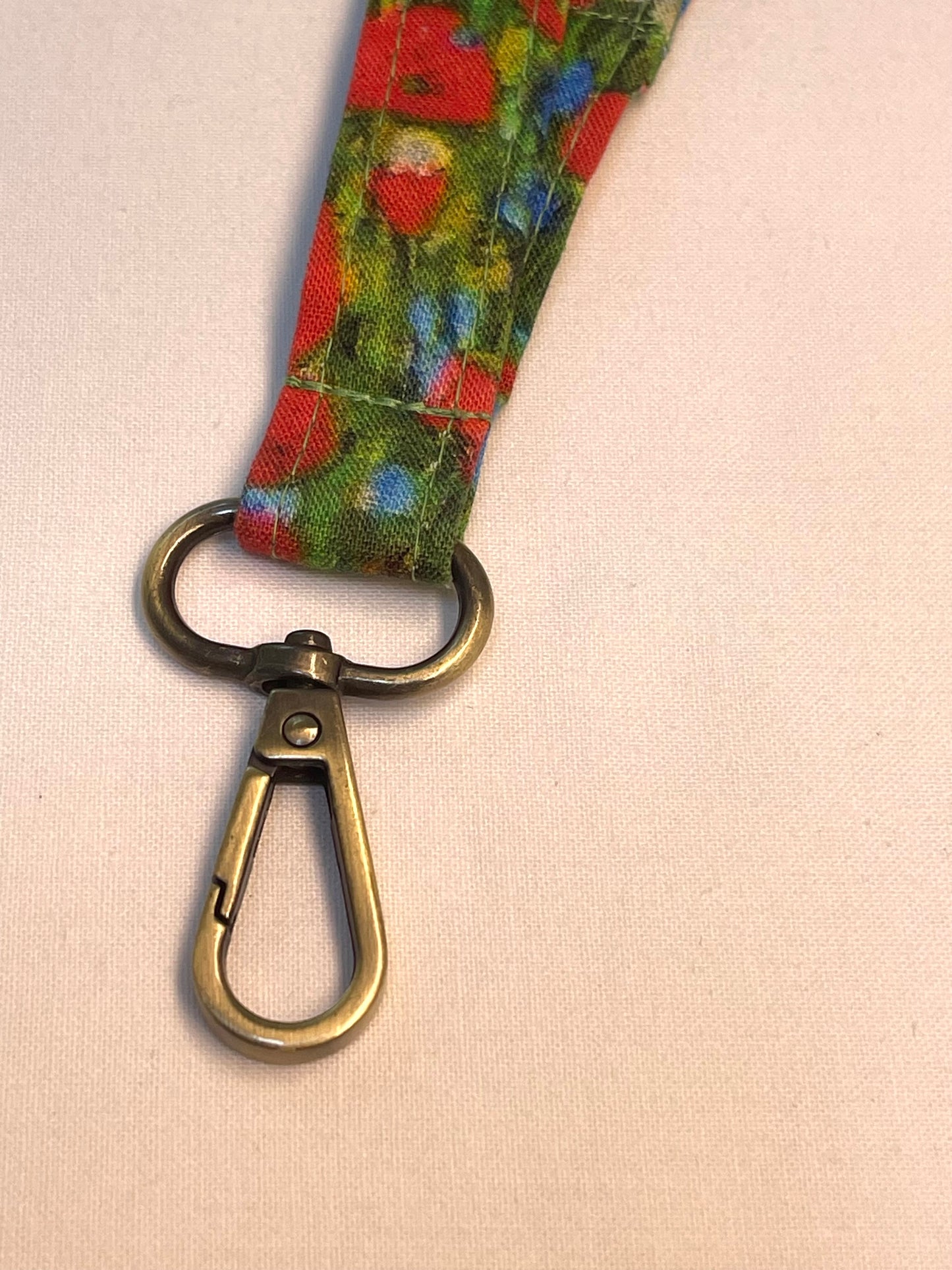 Floral patterned lanyard with a metal clasp on a beige background