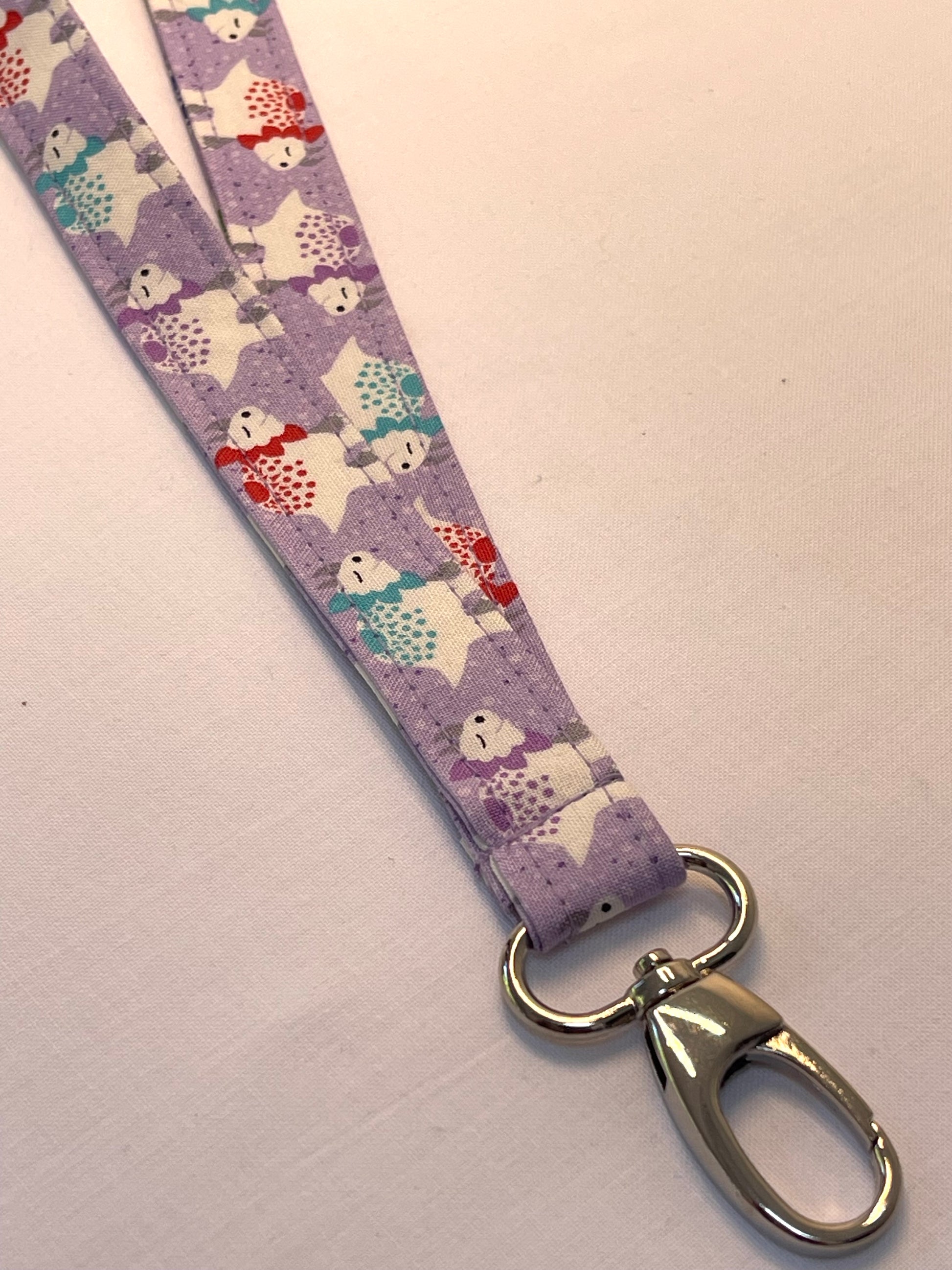 Lanyard with cartoon dinosaur pattern on a light purple background