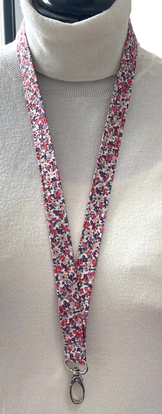 Floral patterned lanyard on a mannequin with a white turtleneck sweater.