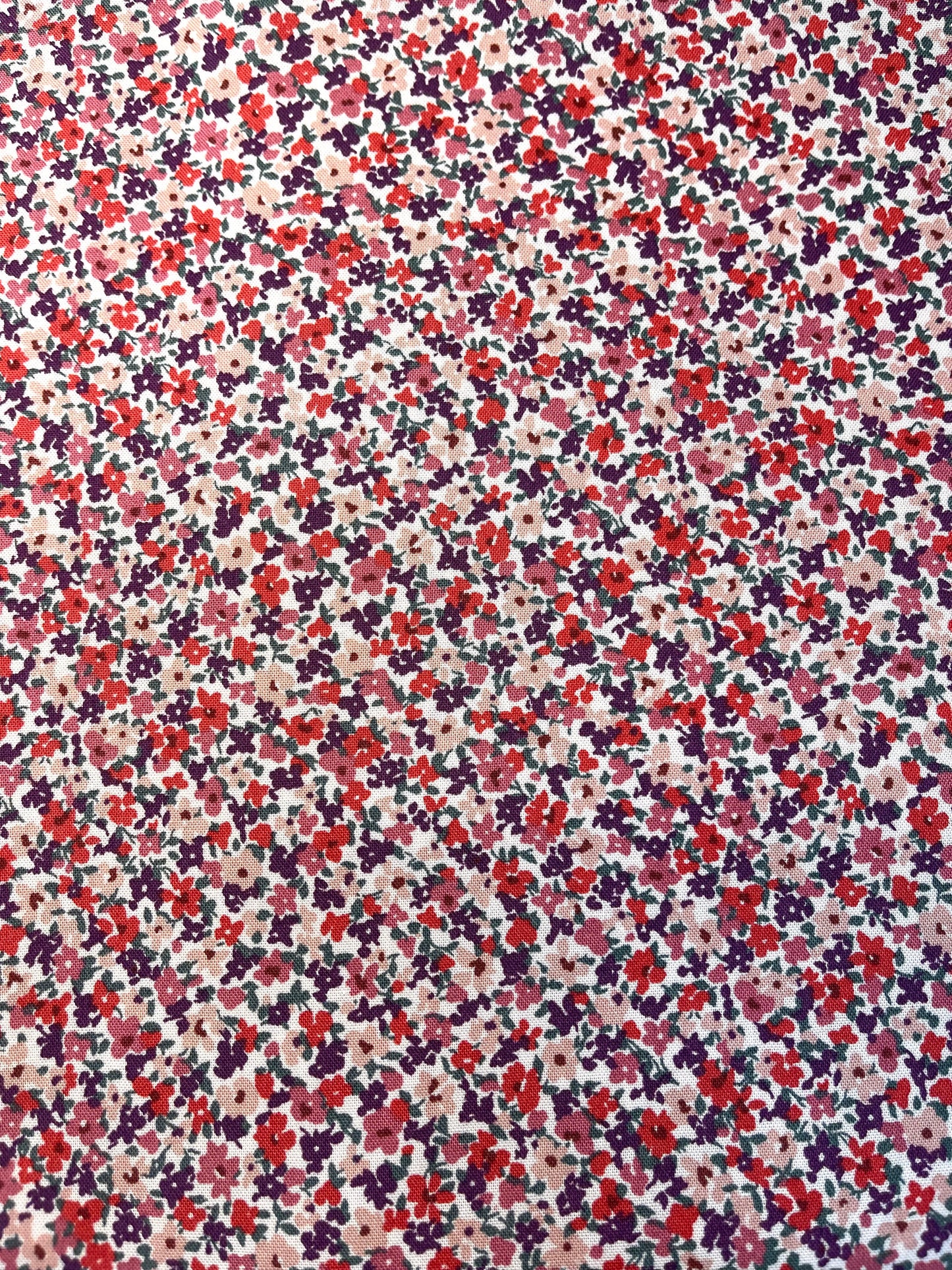 Floral pattern with small flowers in red, purple, and pink on a beige background