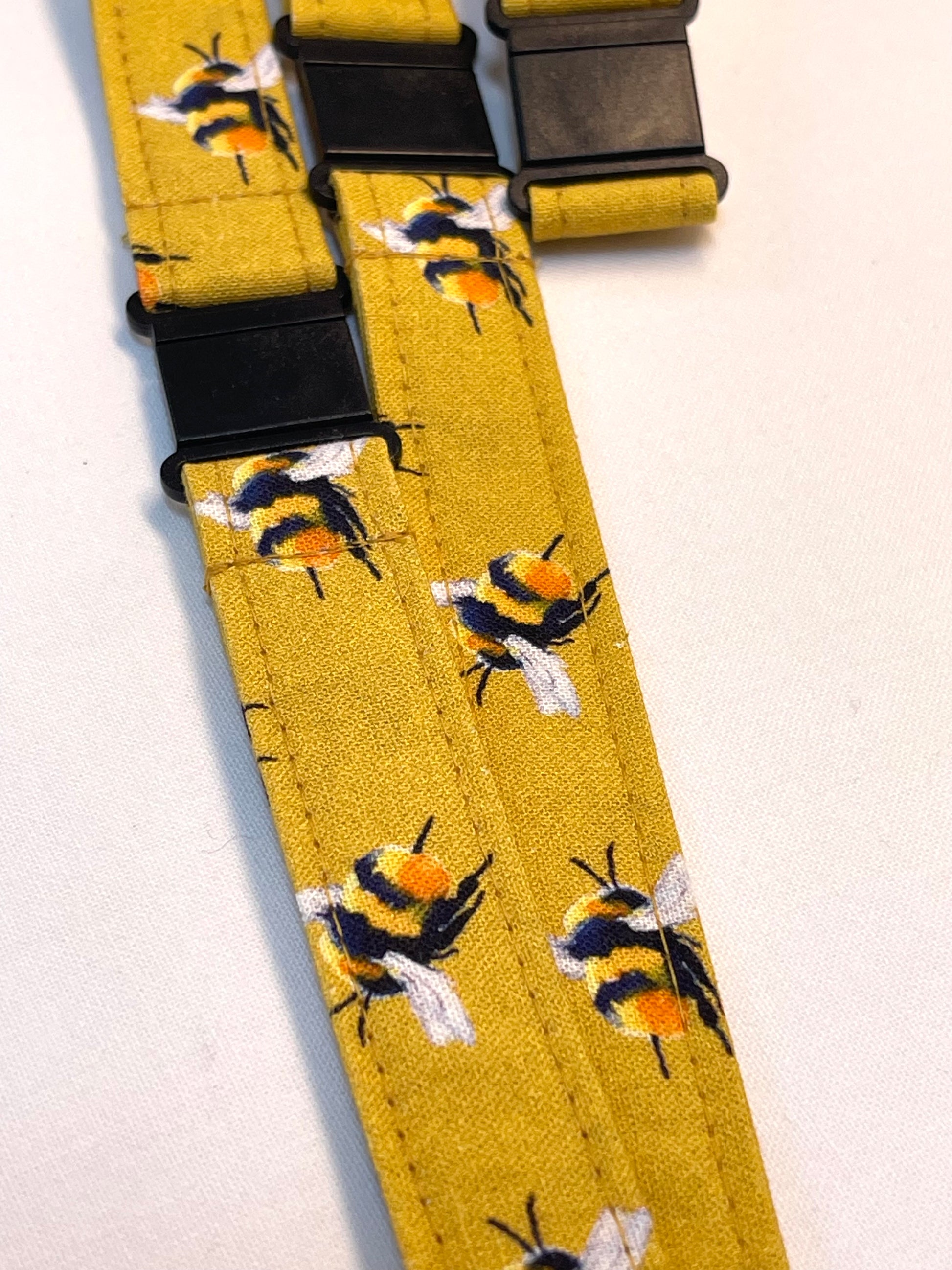 Yellow lanyard with bee pattern and black buckle on a white background