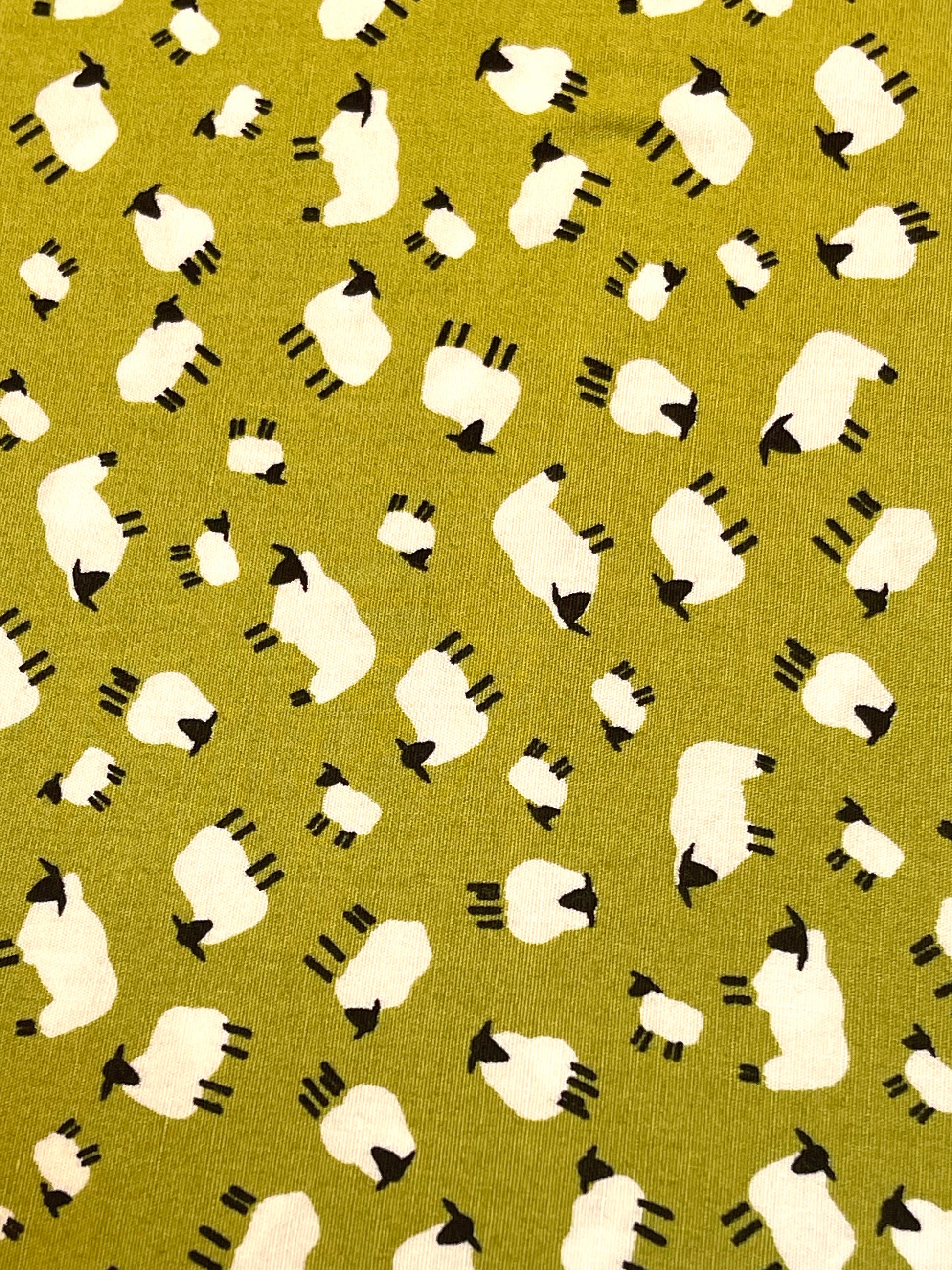 Pattern of white sheep with black faces on a green background