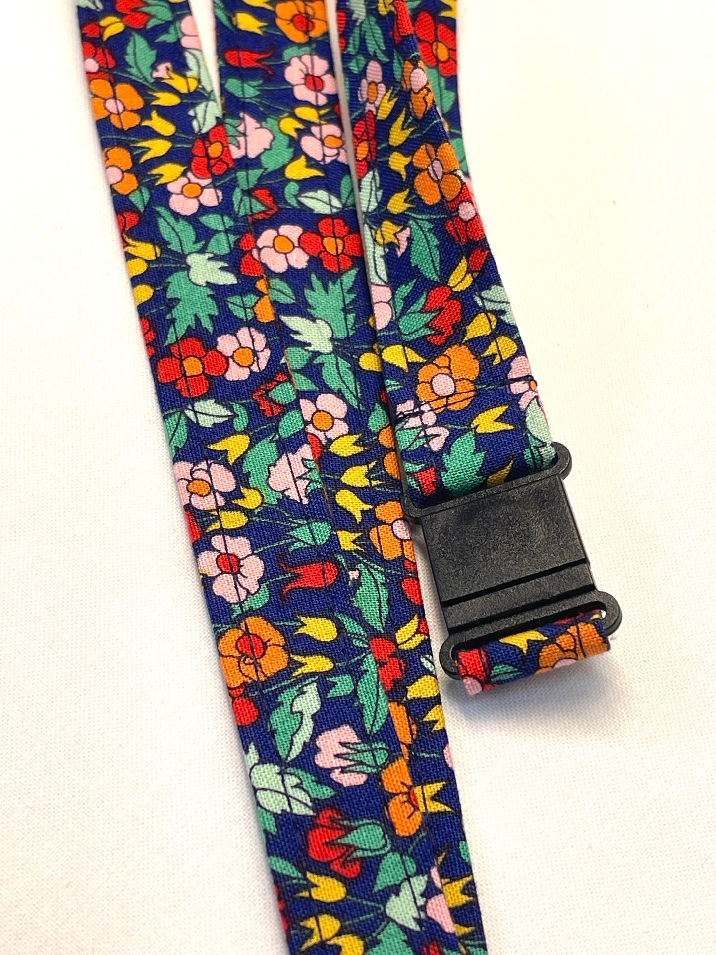 Floral patterned strap with a black buckle on a white background