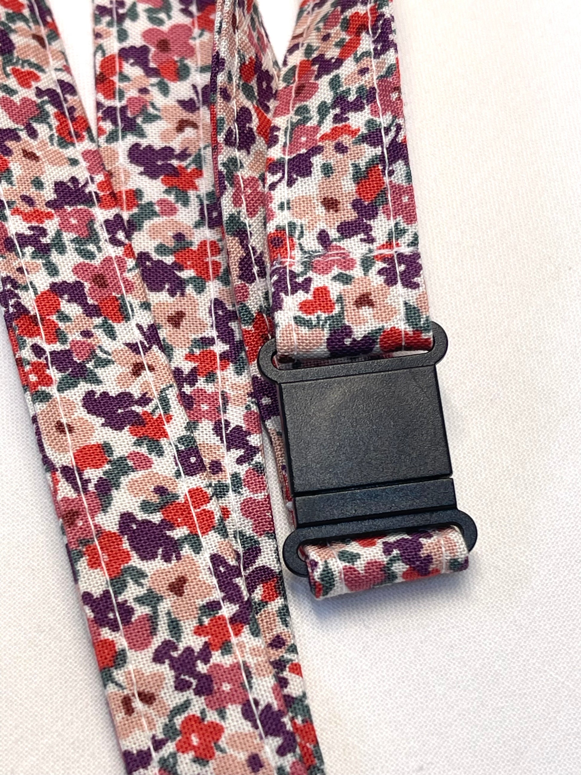 Floral patterned strap with a black buckle on a white background