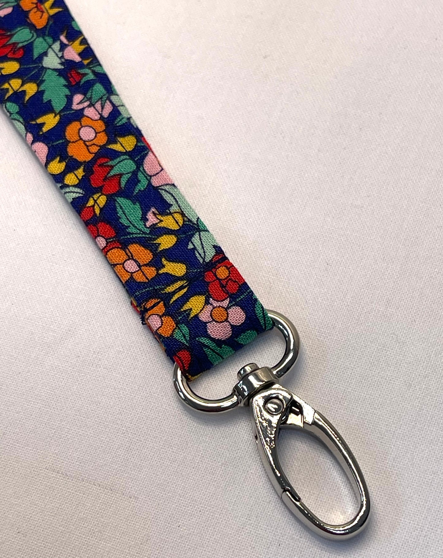 Floral patterned lanyard with a metal clip on a light gray background